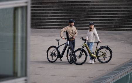 Couple with electric bikes posing outdoors on urban steps. E-bike lifestyle and leisure activities.