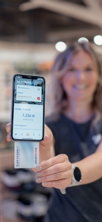Frau hält Smartphone mit geöffneter Mobile-Banking-App und Kreditkarte für digitale Zahlung.