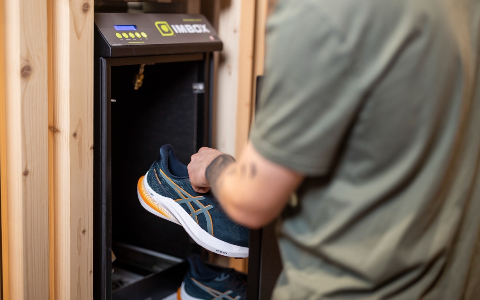 Mann stellt einen Asics-Laufschuh in eine Desinfektionskammer zur Schuhdesinfektion und -reinigung.