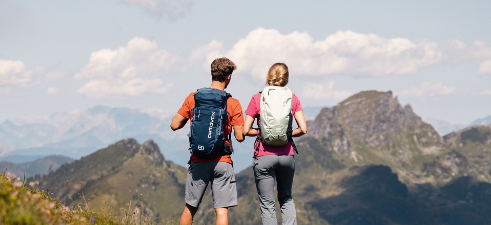 Wanderer mit Rucksäcken genießen die Aussicht auf die Berge. Paar wandert in malerischer Landschaft. Outdoor-Abenteuerreisen.