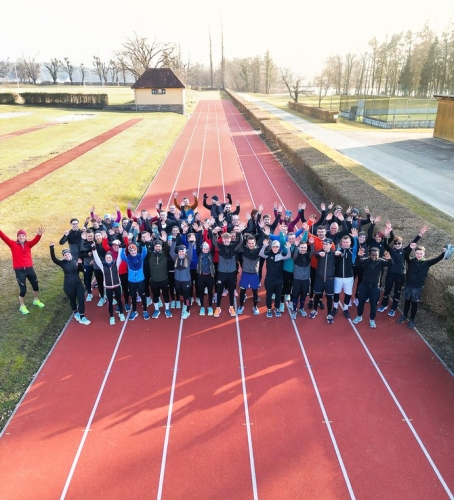 Große Gruppe von Läufern, die auf einer roten Outdoor-Bahn feiern, Fitness- und Sportveranstaltung.