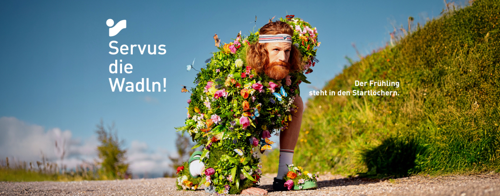 Mann, der im Freien auf einem Parkweg läuft und mit bunten Blumen bedeckt ist, Naturfotografie.