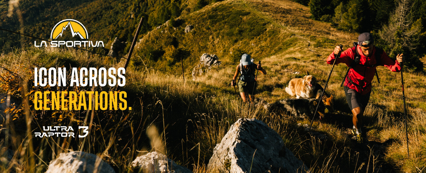 Zwei Trailrunner und ein Hund erklimmen einen sonnigen Bergpfad. Anzeige für La Sportiva Ultra Raptor 3 Outdoor-Schuhe.