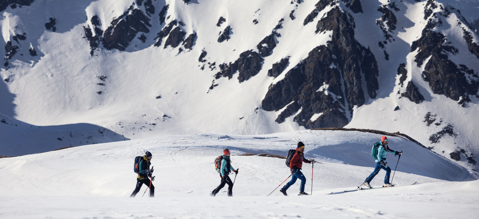 Gruppe von Skitourengehern, die mit Skitourenausrüstung durch eine verschneite Berglandschaft wandern.