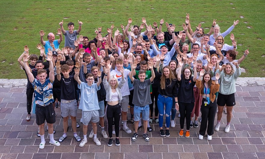 Große Gruppe von Highschool-Schülern hebt im Freien die Hände für ein Foto zur Stärkung des Schulgeists.