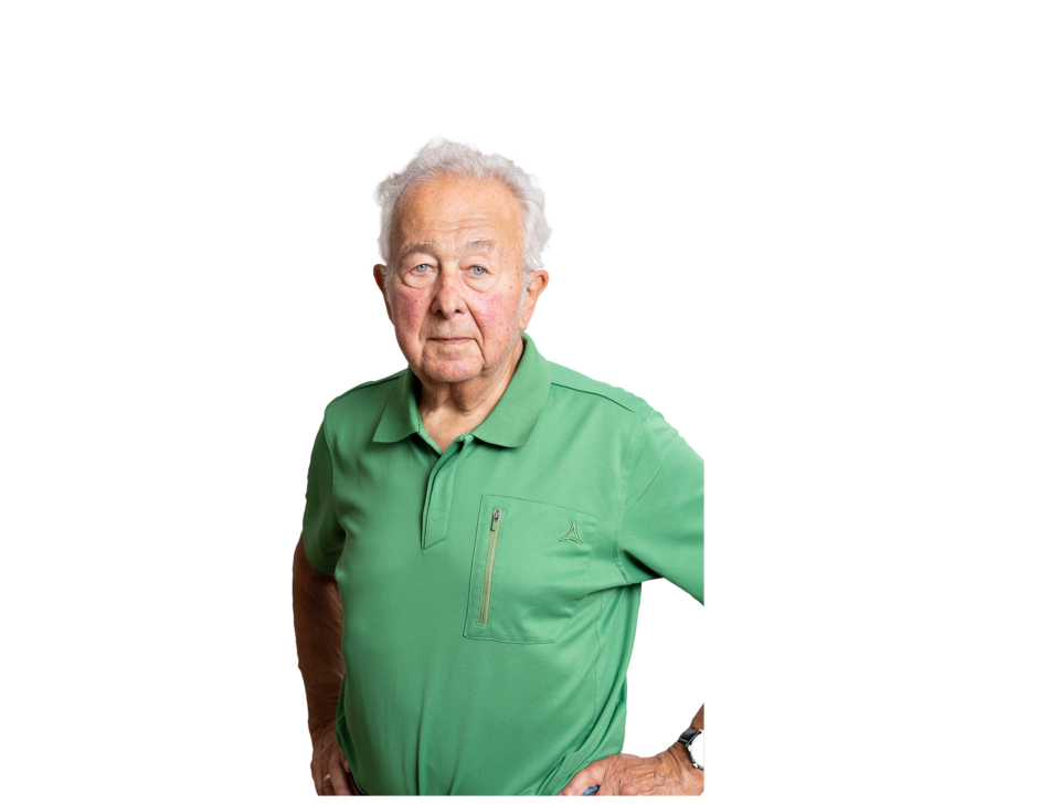 Porträt eines älteren Mannes mit weißen Haaren, der ein grünes Poloshirt vor einem weißen Hintergrund trägt.