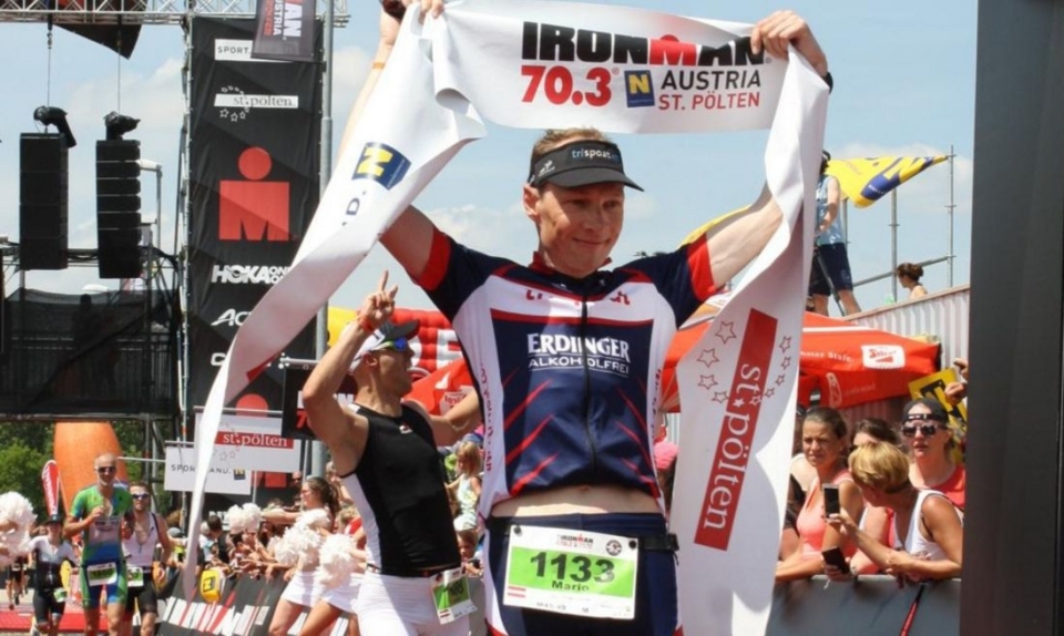 Ironman 70.3 Austria St. Pölten Triathlon Finisher hält Banner und feiert den Rennsieg im Freien.