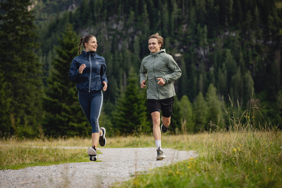 Zwei Frauen laufen auf einem Pfad in den Bergen; Outdoor-Fitness und ein gesunder Lebensstil.