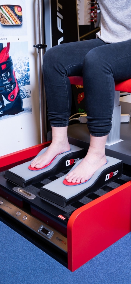 Eine Person benutzt einen Fußscanner zur Anpassung von orthopädischen Schuheinlagen in einem Schuhgeschäft.