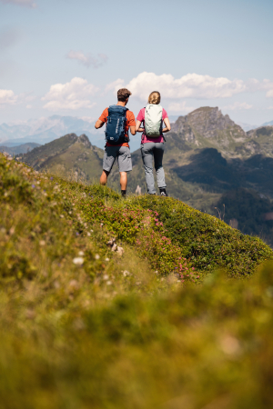 Wanderer mit Rucksäcken genießen die Aussicht auf die Berge. Ein Paar wandert auf einem malerischen Pfad in den Alpen.