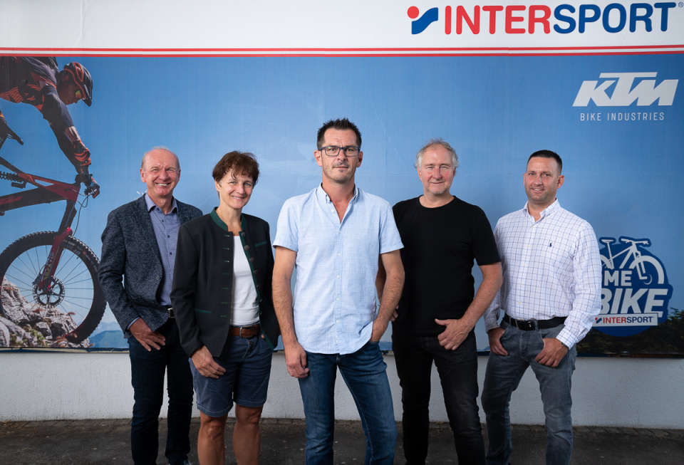 Intersport-Teamportrait mit KTM-Fahrrad-Kulisse zur Bewerbung von Radsport und Outdoor-Sportarten.