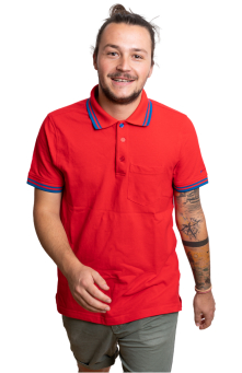 Lächelnder Mann in rotem Poloshirt mit Armtätowierungen geht vorwärts. Lässiges Modeporträt.