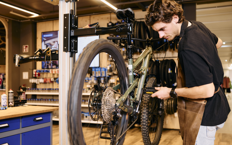 Woman trying on new running shoes in a sporting goods store with assistance from a sales associate.