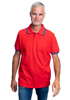 Junger Mann Portrait; lächelnd in rotem Poloshirt mit blauem Saum, Armbanduhr und Tätowierung.