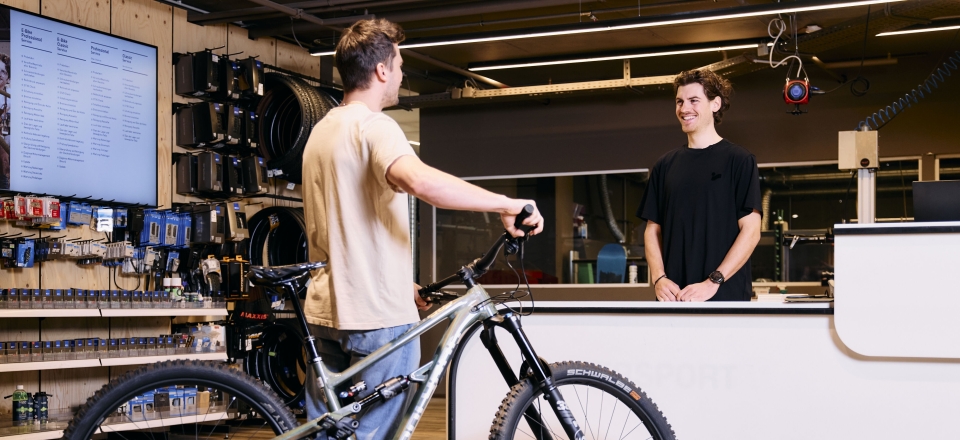 Kunde mit Mountainbike an der Kasse in einem lokalen Fahrradgeschäft.
