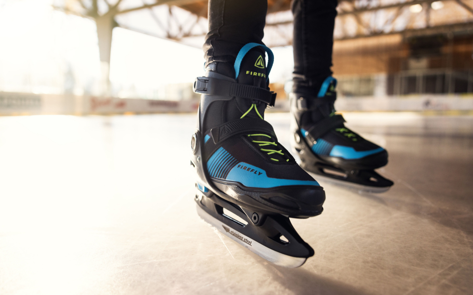 Nahaufnahme von schwarz-blauen Firefly-Schlittschuhen auf einer Eisbahn im Freien, Wintersportausrüstung.