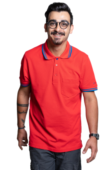 Lächelnder Mann in rotem Poloshirt mit Brille, Armtattoo und dunklen Haaren vor schwarzem Hintergrund.