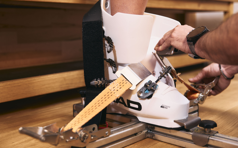 Skischuh-Anpassung: Ein Techniker justiert einen weißen Head-Skischuh in einer professionellen Skiwerkstatt.