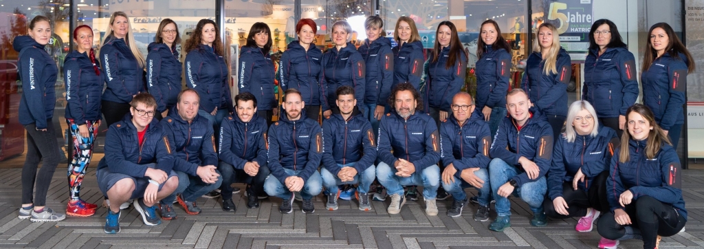 Gruppenporträt eines vielfältigen Business-Teams in einheitlichen marineblauen Jacken mit Branding.