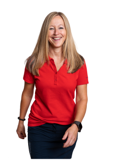 Lächelnde blonde Frau in rotem Poloshirt, die vorwärts geht, isoliert auf weißem Hintergrund.