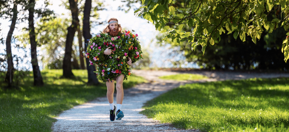 Mann, der im Freien auf einem Parkweg läuft und mit bunten Blumen bedeckt ist, Naturfotografie.